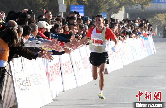 喀什市で沿道を埋め盡くす市民と手をタッチしながら走り過ぎていくランナー（撮影?孫亭文）。