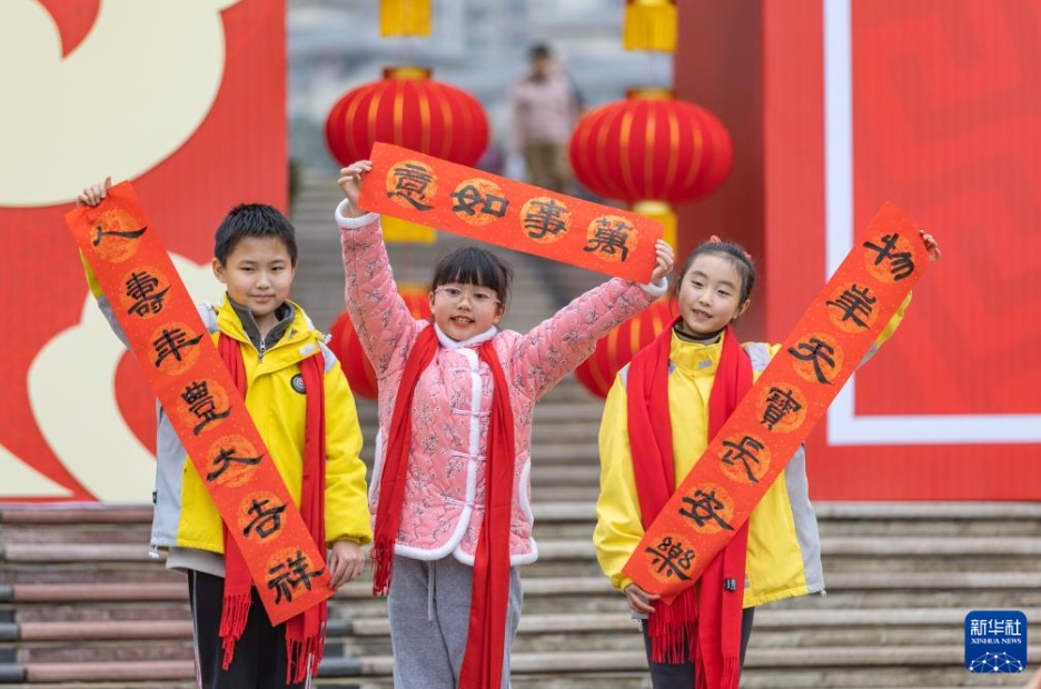 もらった春聯(lián)（春節(jié)に家の玄関などに貼る縁起の良い対句が書かれた赤い紙）を見せる子供たち（撮影?黃偉）。