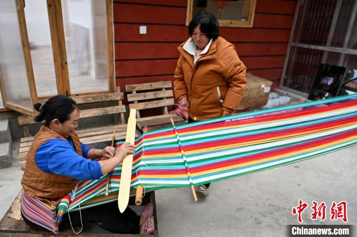 トールン毯を織る仲間と工房で言葉を交わすトールン族の女性?碧玉花さん(寫真右、撮影?李嘉嫻）。