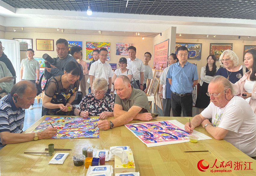 救助に參加した東極島の漁師の子孫である呉小飛さんと共に「漁師畫」を描く「りすぼん丸」の英軍捕虜の子孫（ 撮影?王麗瑋）