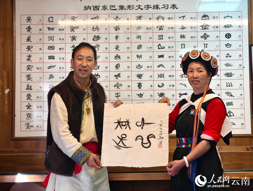 納西象形文字絵畫(huà)體験館を訪れた人民網(wǎng)の取材チームのために、和閏元館長(zhǎng)が取材企畫(huà)名の「行進(jìn)中國(guó)（中國(guó)を行く）」をトンパ文字で書(shū)いてくれた。（撮影?符皓）