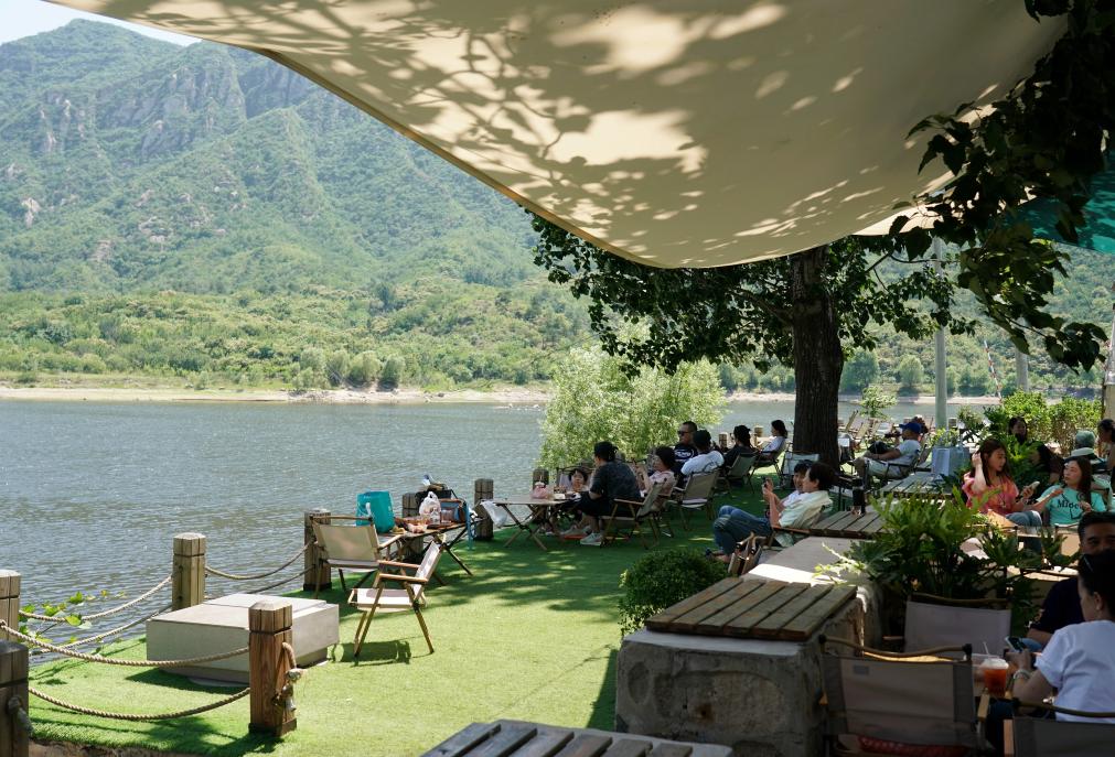 6月12日、「河茵カフェ」で美しい自然の景色を見ながらコーヒーを飲む観光客たち（撮影?張晨霖）。
