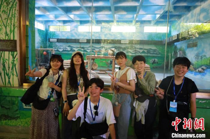 柳州でパンダをバックに記念寫真を撮る日本の若者たち（7月25日撮影?林馨）。