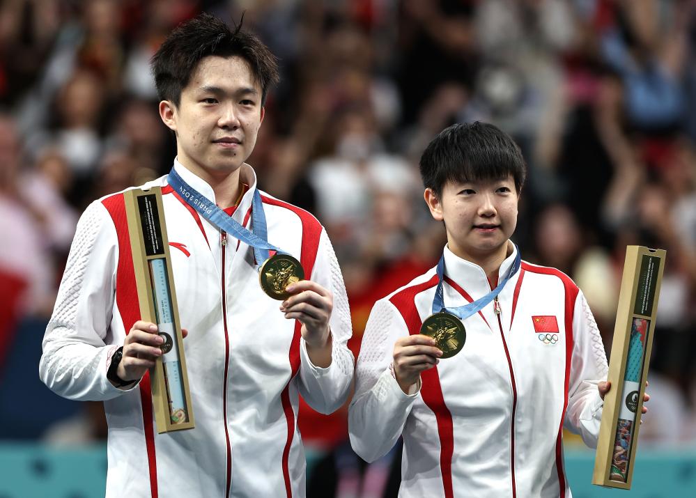 表彰式で金メダルを見せる王楚欽選手(寫真左)/孫穎莎選手ペア（7月30日撮影?王東震）。