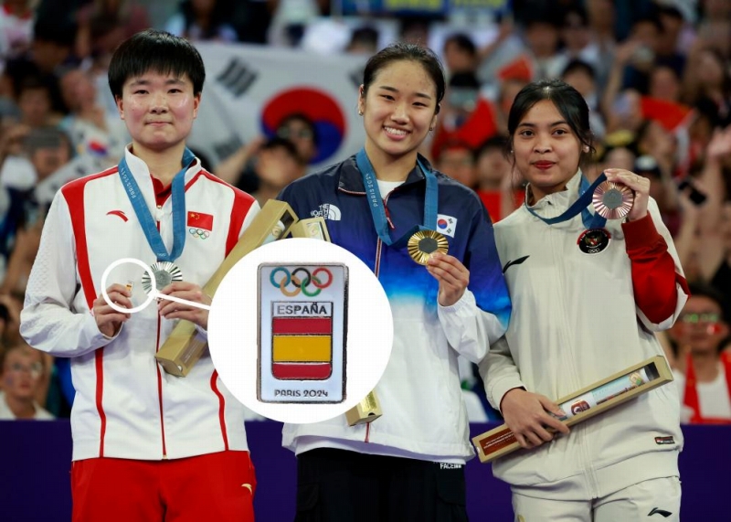 パリ五輪のバドミントン女子シングルス表彰式でスペイン五輪委員會(huì)のピンバッジを手に表彰臺(tái)に上がった何氷嬌選手（撮影?任正來(lái)、寫(xiě)真編集?田光雨）。