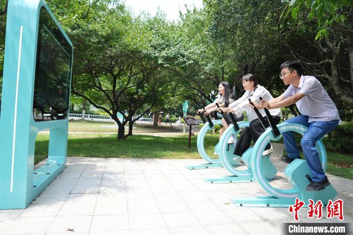 14日、エアロバイク発電を體験する観光客。
