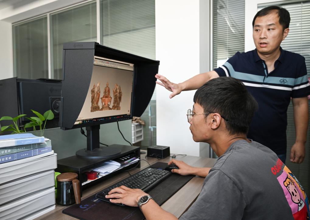 敦煌研究院文化財デジタル化研究所で、莫高窟彩色塑像の3D再建作業(yè)の成果を示すスタッフ。（撮影?李賀）