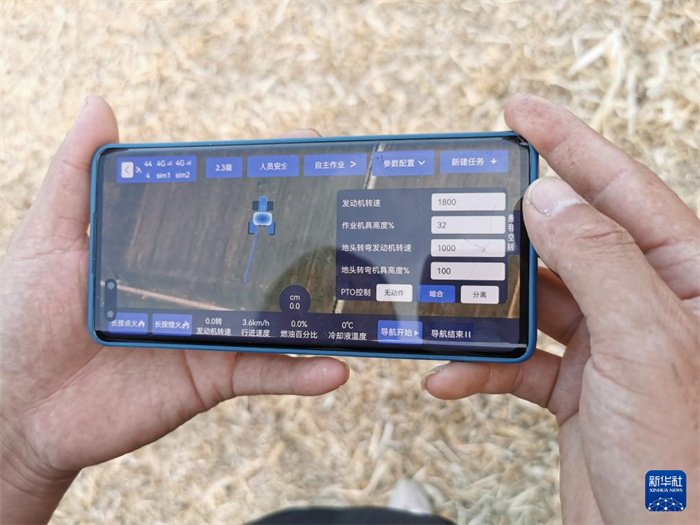 作業(yè)現(xiàn)場で11日、自動運転トラクターを遠(yuǎn)隔操作する攜帯電話の畫面を見せてくれた張先智氏。撮影?馬意翀