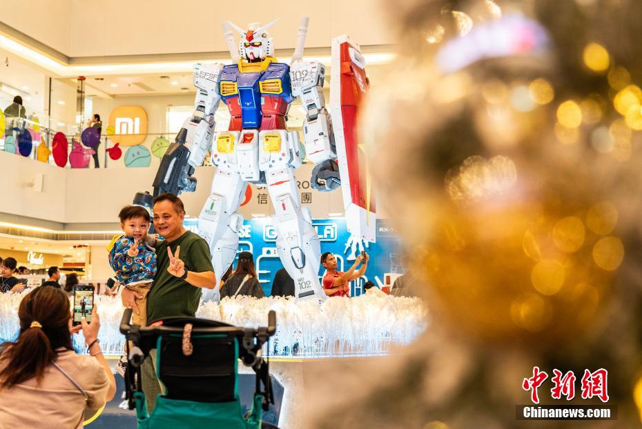 高さ3メートルの初代ガンダムRX-78-2の立像の前で記念撮影する市民や観光客（撮影?侯宇）。
