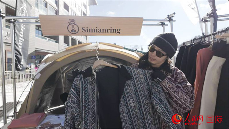 自身がデザインしたスノーボードウエアを見せる藤田周さん（撮影?袁蒙）。