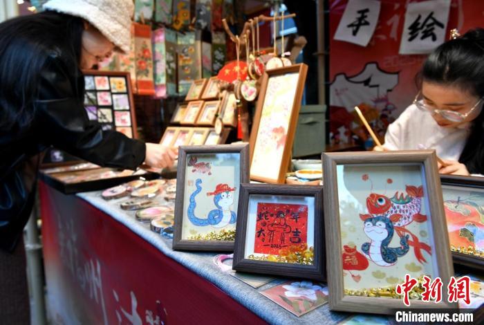    福建省福州市上下杭?xì)s史文化街區(qū)(エリア)で開催された新春マーケットで、「巳年」がテーマの文化クリエイティブグッズを選ぶ女性（1月17日撮影?呂明）。