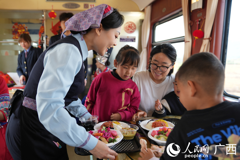 無形文化遺産メニューを乗客の元に運ぶ女性スタッフ（撮影?王勇）。