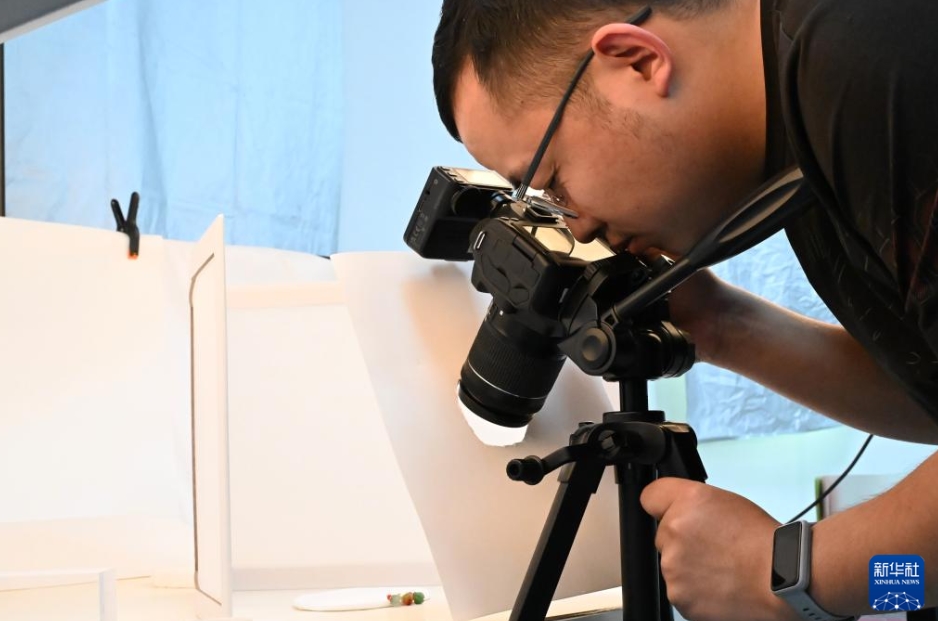 浙江省溫州市永嘉県橋頭鎮(zhèn)にあるボタンメーカーで、ボタンのPRポスターを撮影するスタッフ（3月26日撮影?隋尚君）。