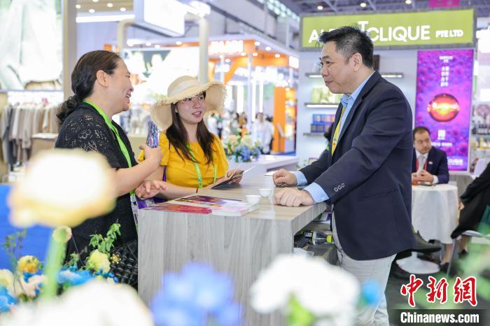 海南省?？谑肖情_(kāi)催中の消費(fèi)財(cái)博のシンガポールの企業(yè)のブースで説明を聞く女性たち（4月14日撮影?駱雲(yún)飛）。