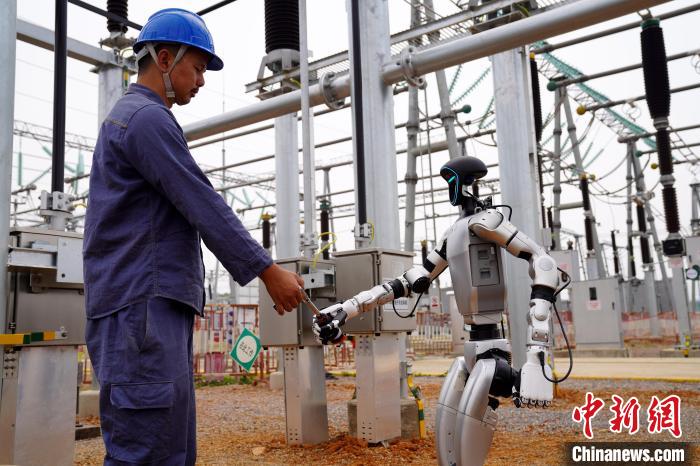 220kV吉安変電所作業(yè)現(xiàn)場で工具の受け渡しを行う人型ロボットと作業(yè)員（撮影?馬莎）。