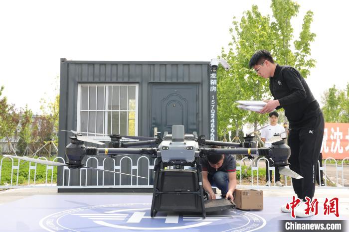 ドローンが配送ステーションの離著陸地點に無事著陸し、貨物受取人の學生に引き渡す準備を行う順豊速運のスタッフ。（寫真提供：輝山経済技術開発區(qū)）