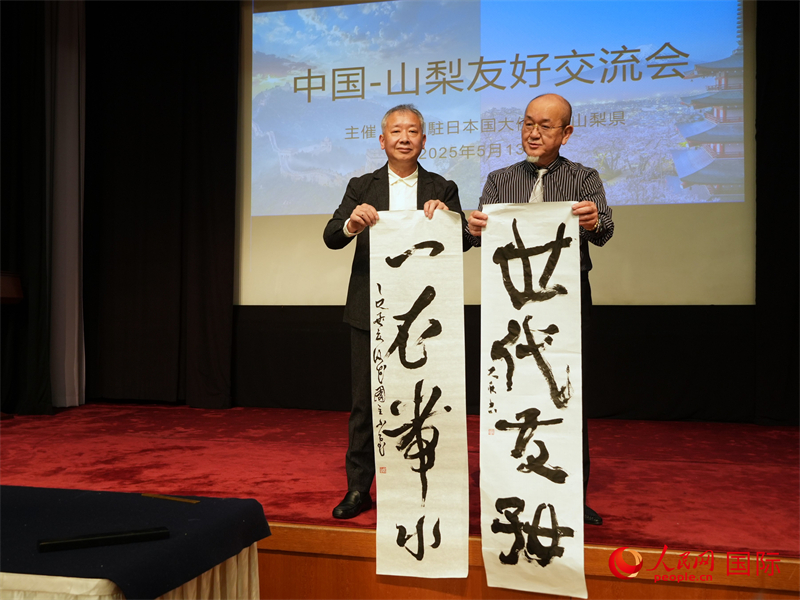 寫真：「一衣帯水」「世代友好」と揮毫した作品を手にする両國の書道家。（撮影?許可）