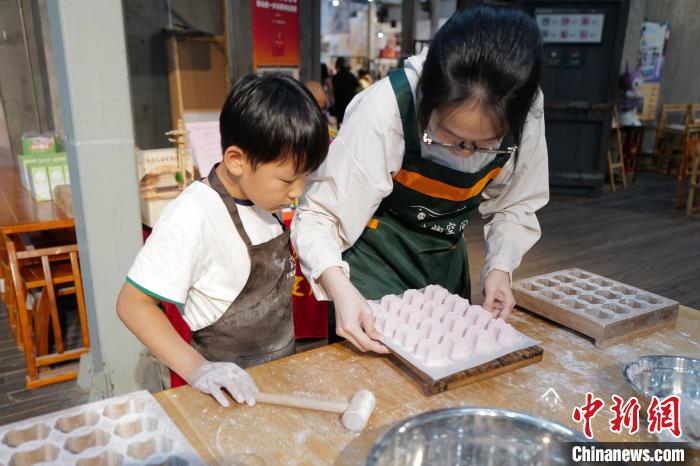 スタッフの指導(dǎo)の下、蘇州など江南地方で食べられる伝統(tǒng)的な蒸し菓子「定勝糕」を制作する子供（6月2日撮影?張煜歓）。