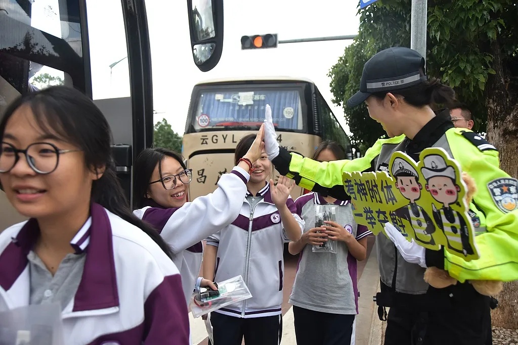 6月7日、雲(yún)南省紅河哈尼（ハニ）族彝（イ）族自治州蒙自市の第一高級中學(xué)校の試験會場前でエールを送るために、受験生とハイタッチする女性警察官。