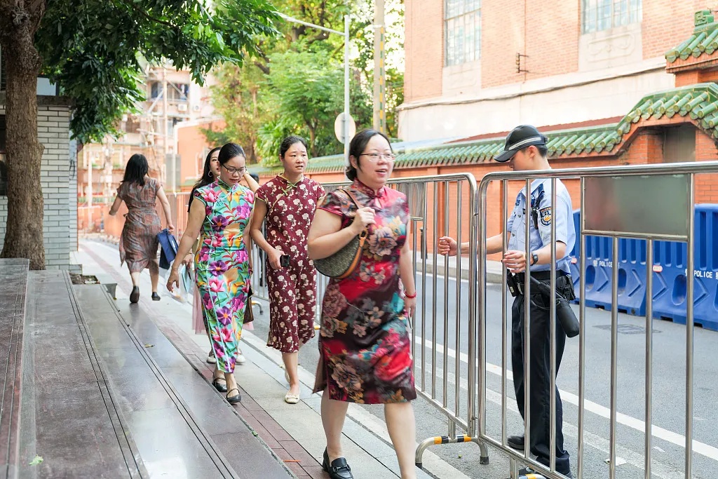 6月7日、2025年高考が始まった広東省広州市の広州第七中學(xué)校の試験會場前を、チャイナドレスを著て歩く受験生の保護者。