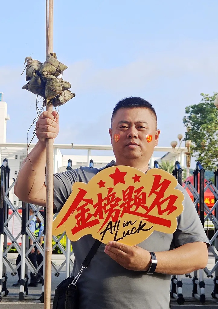 良い成績を収めるという意味の「一挙高中」にかけて「粽(中國語の「中」と発音が似ている)」を「挙」げてゲン擔(dān)ぎする受験生の父親。