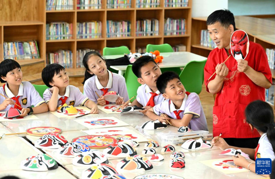 石家荘市裕華西路小學(xué)校で児童たちに、京劇の臉譜の絵付けを紹介する張建認(rèn)さん（6月10日撮影?陳其保）。