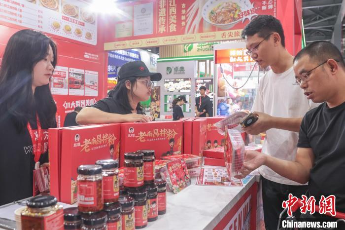 2025ライスヌードル産業(yè)交易會で、ライスヌードル関連の商品について質問をする男性。（6月13日撮影?劉力鑫）