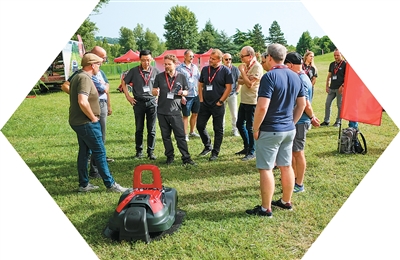 イタリアのボローニャで開催された販売代理店會議で、格力博製のスマートロボット芝刈り機?AiConicの性能をチェックする外國人バイヤーら（撮影?楊旻）。