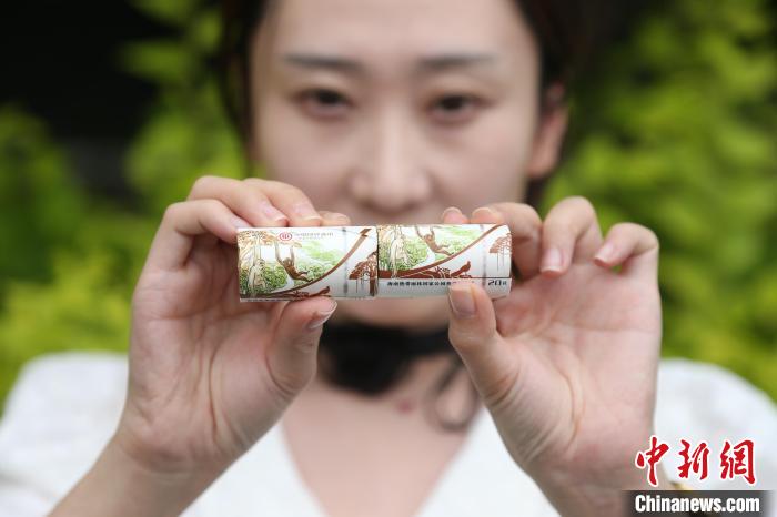青海省西寧市で、海南熱帯雨林國(guó)家公園の記念コインのパッケージを見(jiàn)せる女性（6月17日撮影?張忠蘋(píng)）。
