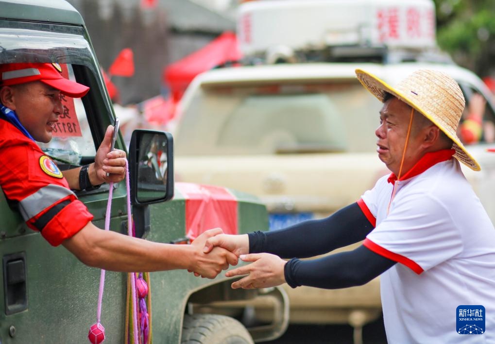 貴州省榕江県から帰途に就く救援チームのメンバーと握手する男性（7月3日撮影?龍順偉）。