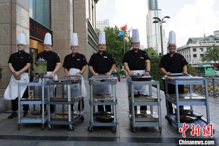 ホテル外で販売する料理を乗せたワゴンを前に立つシェフたち（撮影?趙夢(mèng)陽(yáng)）。