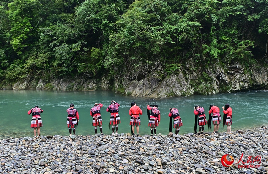 紅瑤の伝統(tǒng)衣裝を著て川辺で長(zhǎng)い髪を梳く女性たち。（撮影?雷琦竣）