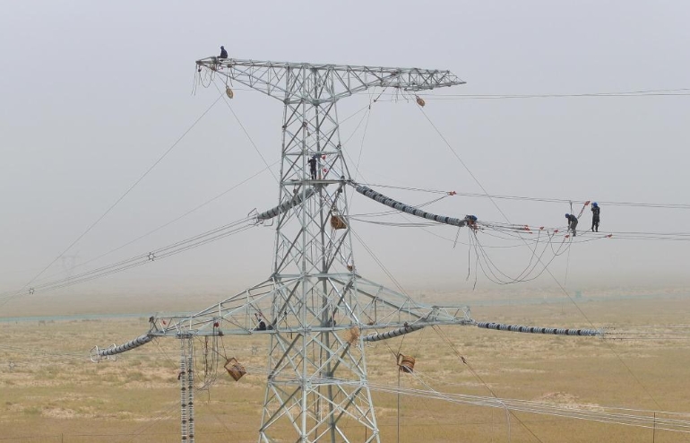 7月12日、陳林さん（右から1人目）と同僚が新疆維吾爾（ウイグル）自治區(qū)和田（ホータン）地區(qū)民豊県の工事現(xiàn)場(chǎng)で、送電線(xiàn)の架線(xiàn)作業(yè)を進(jìn)める様子。（ドローンによる撮影）