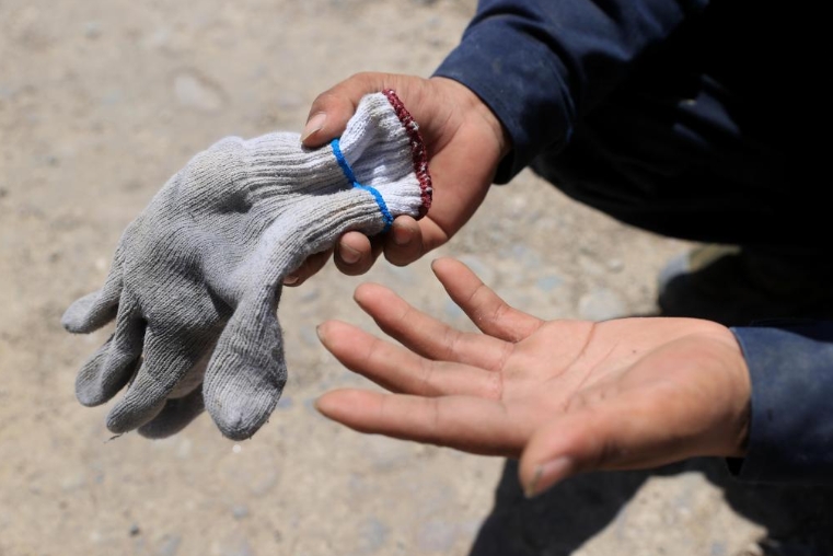 7月13日、新疆維吾爾（ウイグル）自治區(qū)和田（ホータン）地區(qū)民豊県の工事現(xiàn)場(chǎng)で作業(yè)を終え、手袋を外した陳林さん。