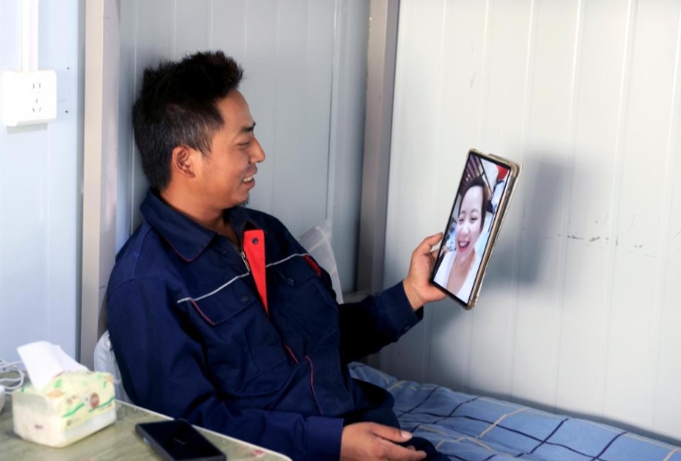 7月10日、新疆維吾爾（ウイグル）自治區(qū)和田（ホータン）地區(qū)民豊県の工事現(xiàn)場(chǎng)宿舎で、休憩中に妻の王麗さんとテレビ電話(huà)で通話(huà)する陳林さん。