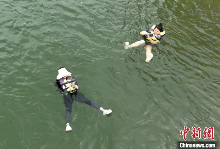 水に浮かびながらスマホで遊ぶ観光客（7月14日、ドローンによる撮影?王剛）