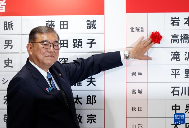 東京の自民黨本部で20日、當(dāng)選した議員の名前の上に花を添える石破茂首相。