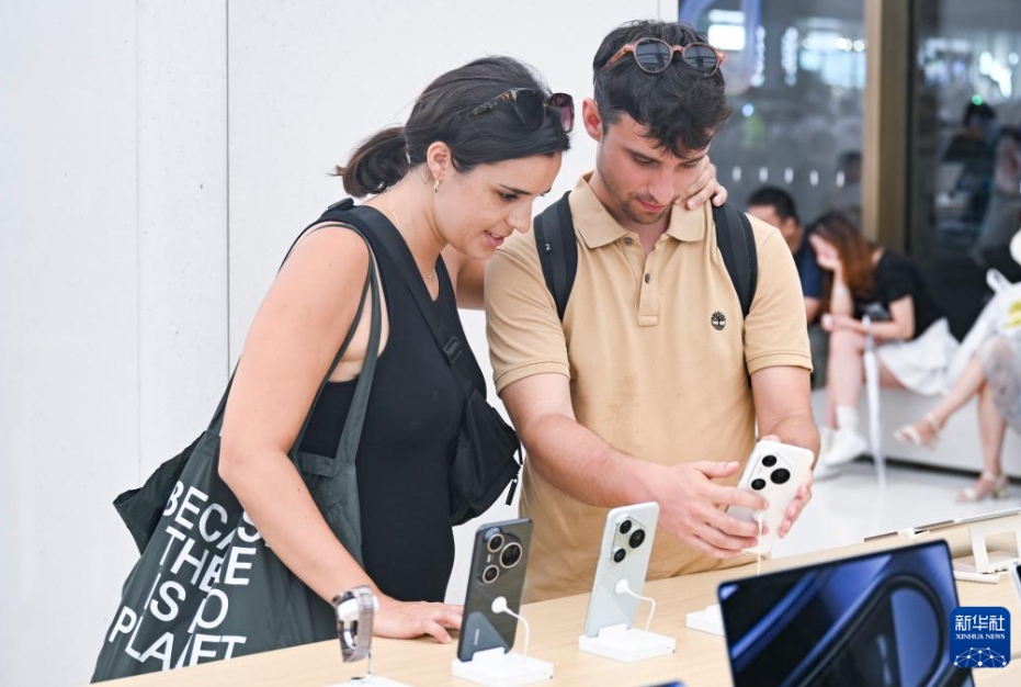 上海市南京路にある華為（ファーウェイ）の店舗で、スマホを見る2人のスペイン人観光客（7月17日撮影?陳浩明）