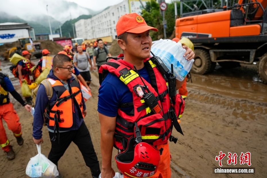 救援物資を持って、北京市懐柔區(qū)琉璃廟鎮(zhèn)の山間部にある村に徒歩で向かう消防隊員。（7月28日撮影?趙文宇）