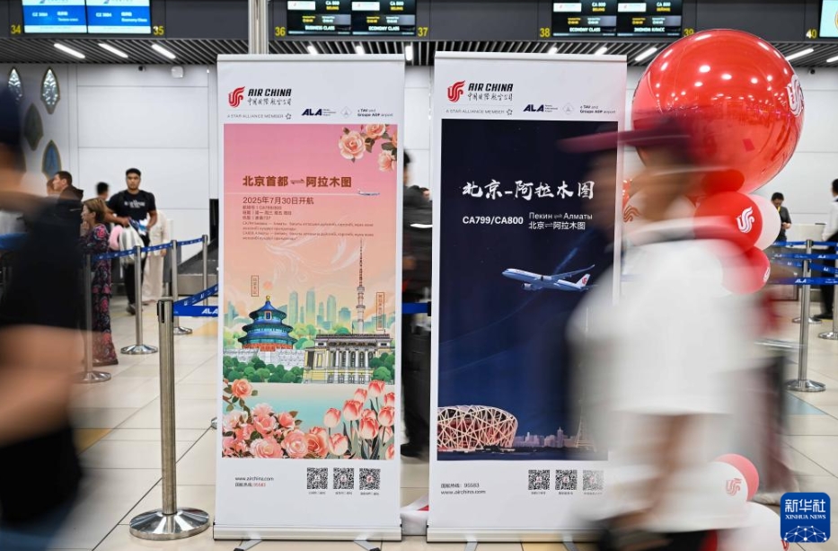 カザフスタンのアルマトイ國際空港で、中國國際航空が運航する北京－アルマトイ直行便のPRポスターの前を通り過ぎる乗客（7月30日撮影?李任滋）