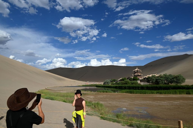 甘粛省敦煌市鳴沙山月牙泉景勝地で記念寫真を撮影する女性（6月21日撮影?張暁亮）