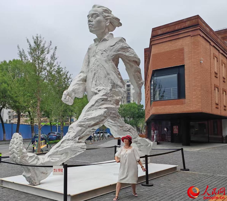 來天美蕓術(shù)街區(qū)に設(shè)置されている巨大オブジェのポーズをまねる中高年女性（撮影?張靖）。