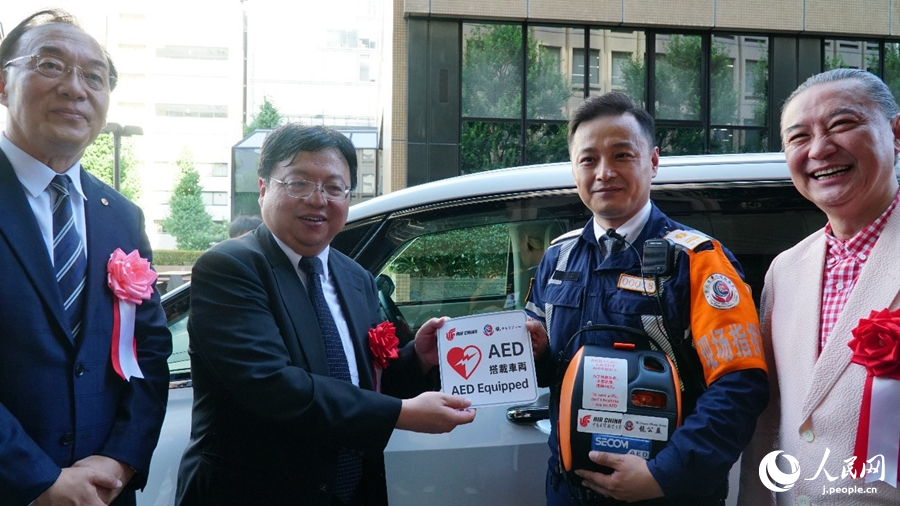 ボランティアと共にAED搭載車両ステッカーを貼るゲスト（撮影?蔣暁辰）。