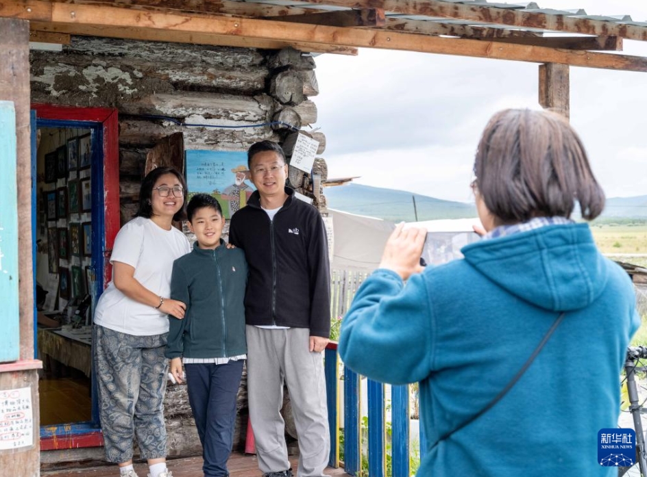 內(nèi)蒙古自治區(qū)恩和俄羅斯族民族郷で、オロス族の伝統(tǒng)的木造家屋「木刻楞」の前で記念寫(xiě)真を撮影する観光客（8月21日撮影?馬金瑞）