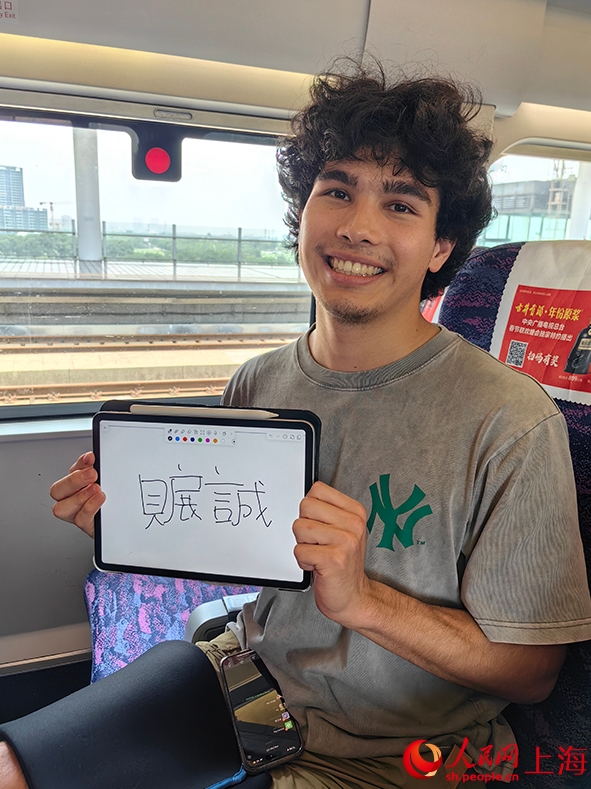 記者に自身の中國名「貝展誠」を書いてみせるアリスターさん（撮影?唐小麗）