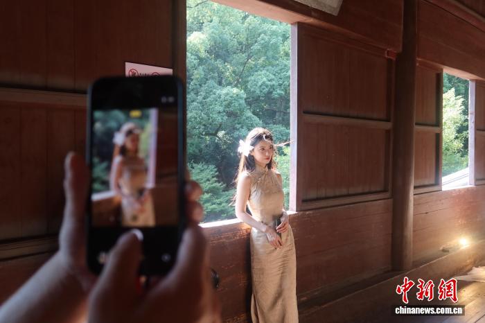 六和塔の木製の窓をバックに寫真を撮影する女性（8月30日撮影?孫琳茹）。