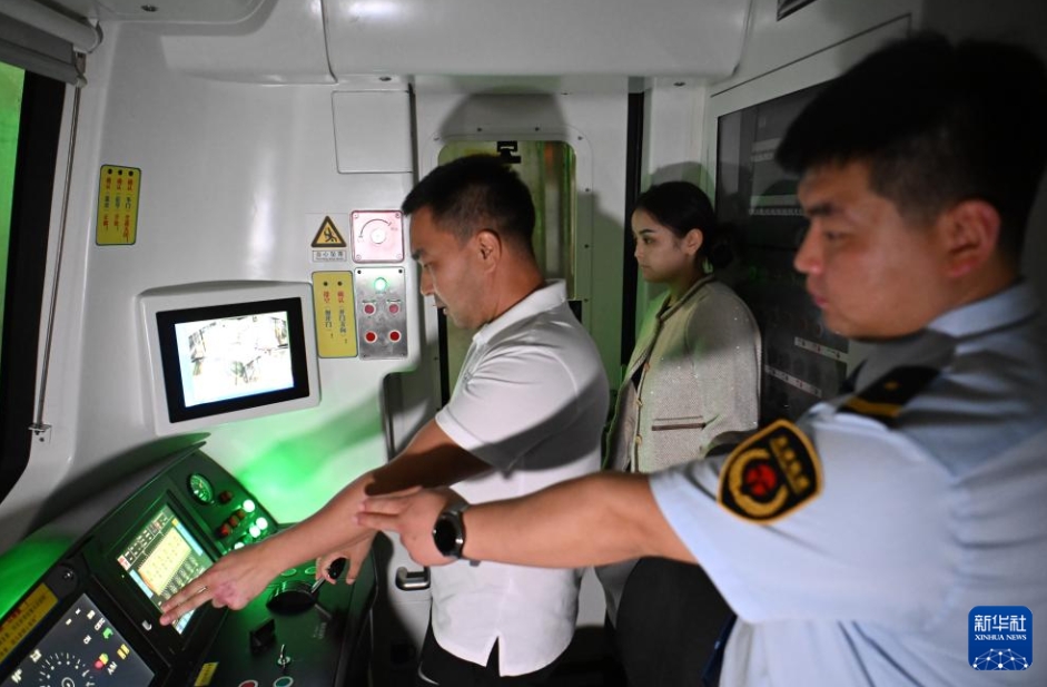 夜間に天津地下鉄10號線の梨園頭車両區(qū)間で、教官の張垚さん（寫真右）の指導(dǎo)の下、運(yùn)転の試験を受けるカザフスタン人のダルハンさん（寫真左、9月5日撮影?孫凡越）。