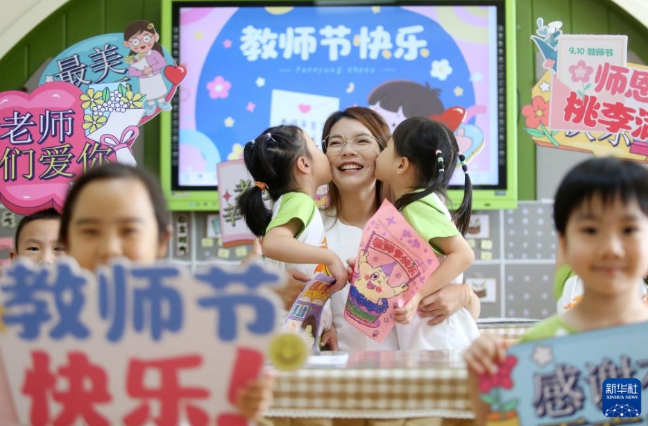 江蘇省揚(yáng)州大學(xué)附屬西郡幼稚園で、先生の頬にキスする園児（9月10日撮影?孟徳龍）。