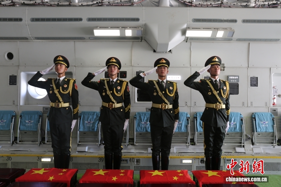 中國(guó)空軍の輸送機(jī)「運(yùn)-20」の機(jī)內(nèi)で、中國(guó)の國(guó)旗がかぶせられた志愿軍烈士の遺骨に向かって敬禮する禮兵（撮影?王鴻飛）。