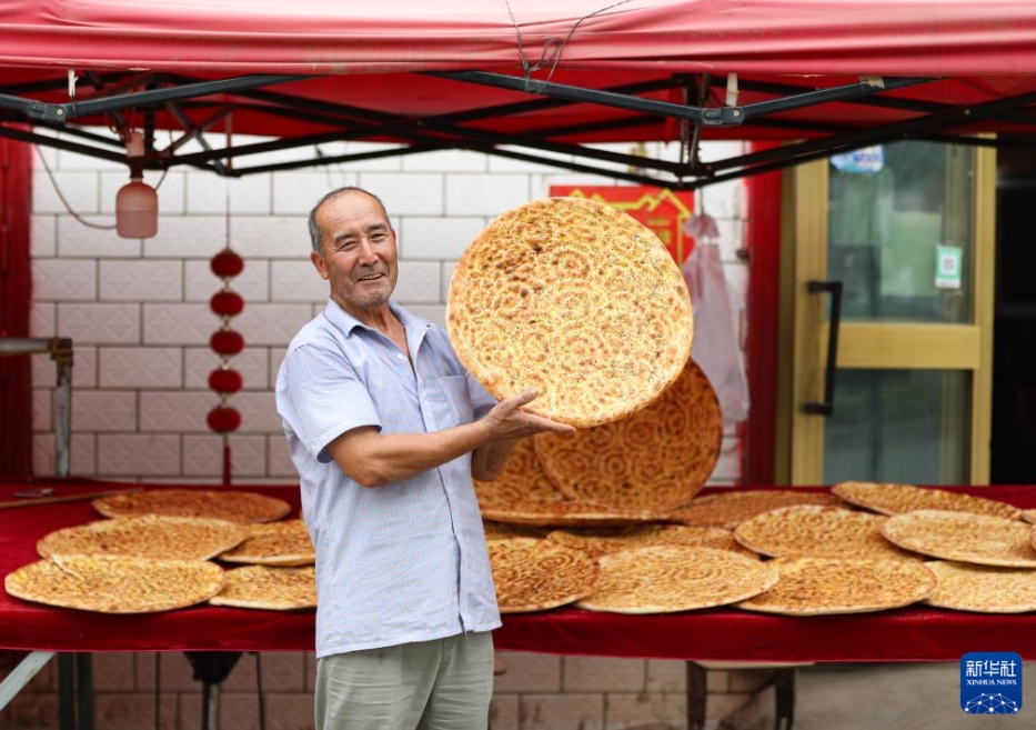 新疆庫(kù)車市で自作のナンを見せる熱西堤さん（7月21日撮影?王婧嬙）。